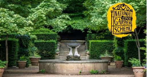 A formal garden with a circular stone fountain in the center, surrounded by potted plants and neatly trimmed hedges. The National Open Garden Scheme logo appears in the top right corner.
