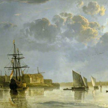 Boats and sailboats on a calm river near a town under a cloudy sky at sunset