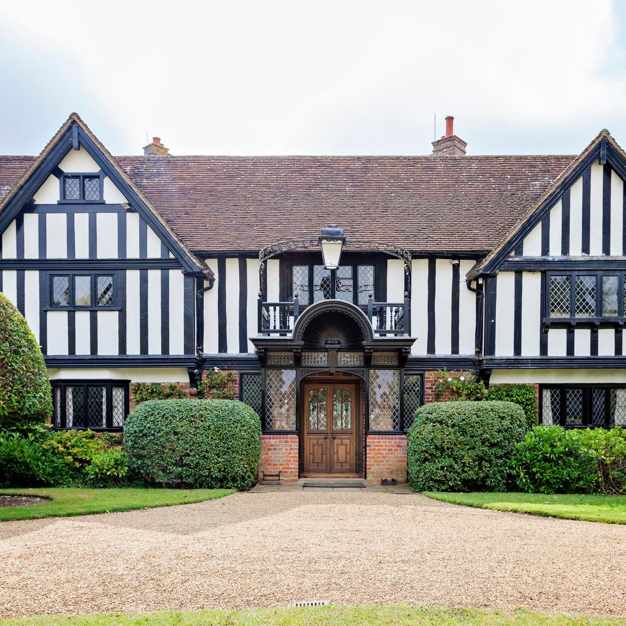 Tudor-style house with timber framing and manicured bushes