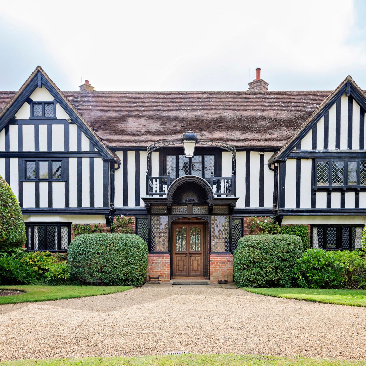 Tudor-style house with timber framing and manicured bushes
