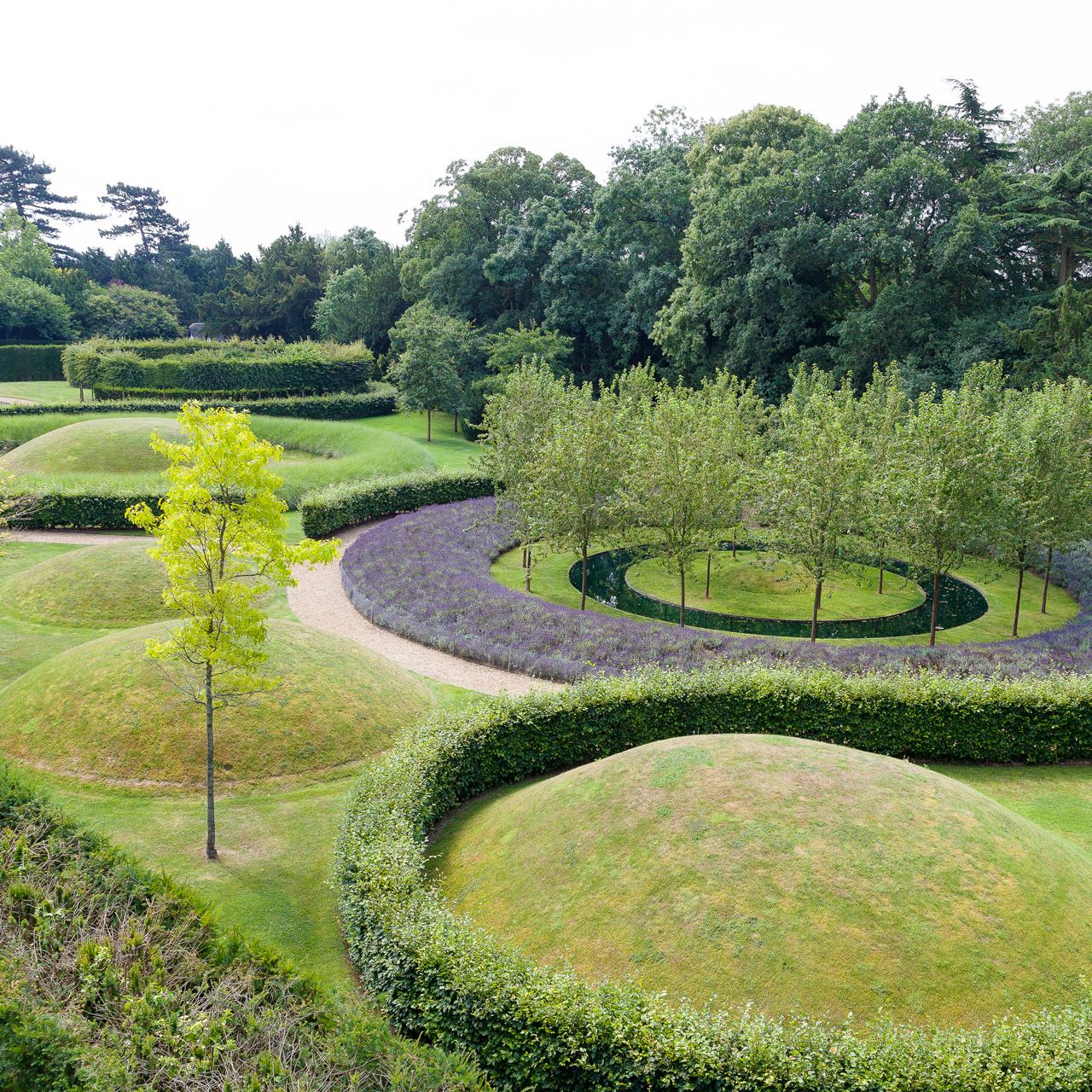Aerial view of a garden with mounded grassy hills, curved paths, and neat hedges