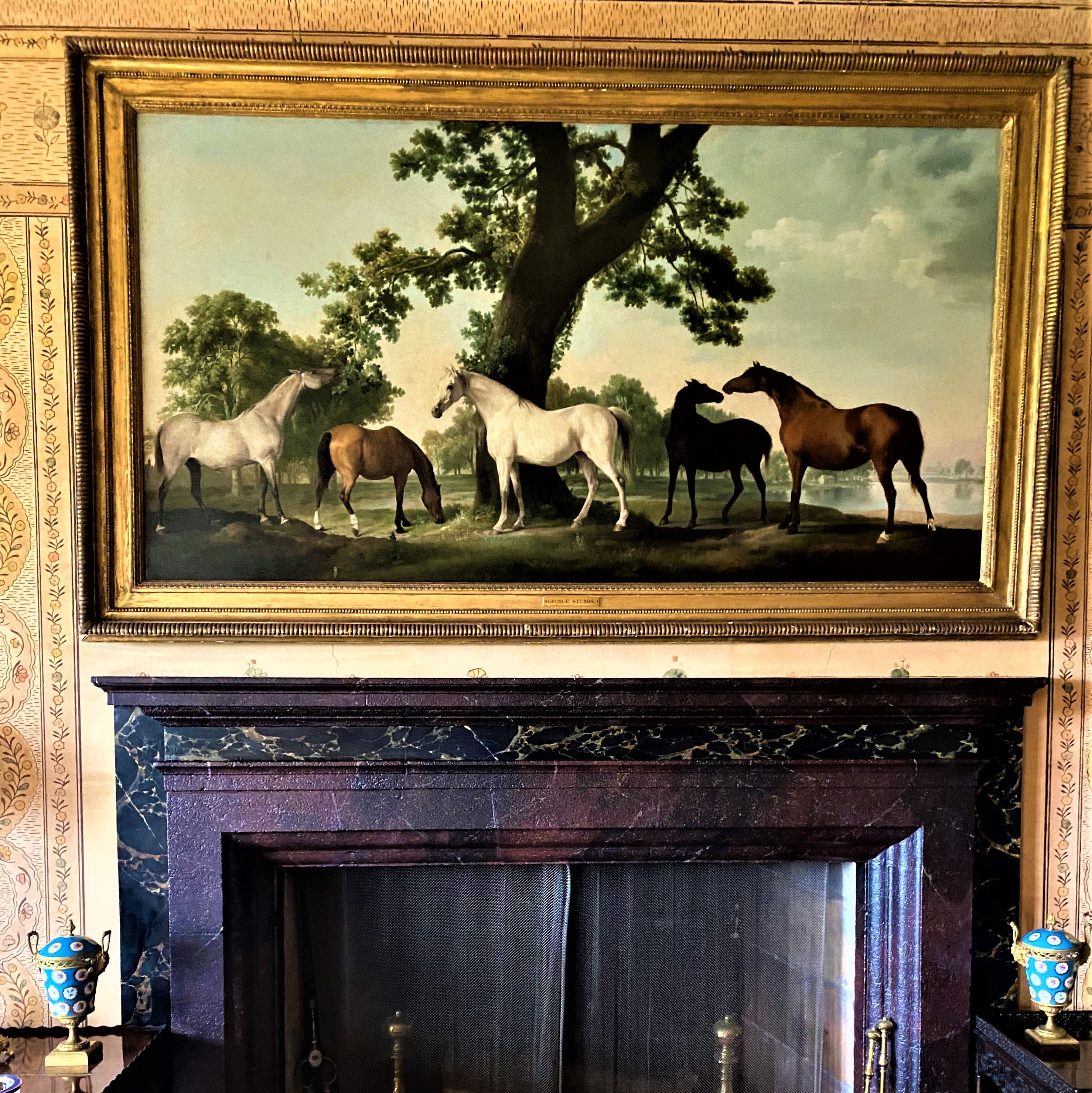Painting of horses in a landscape, hanging above a marble fireplace