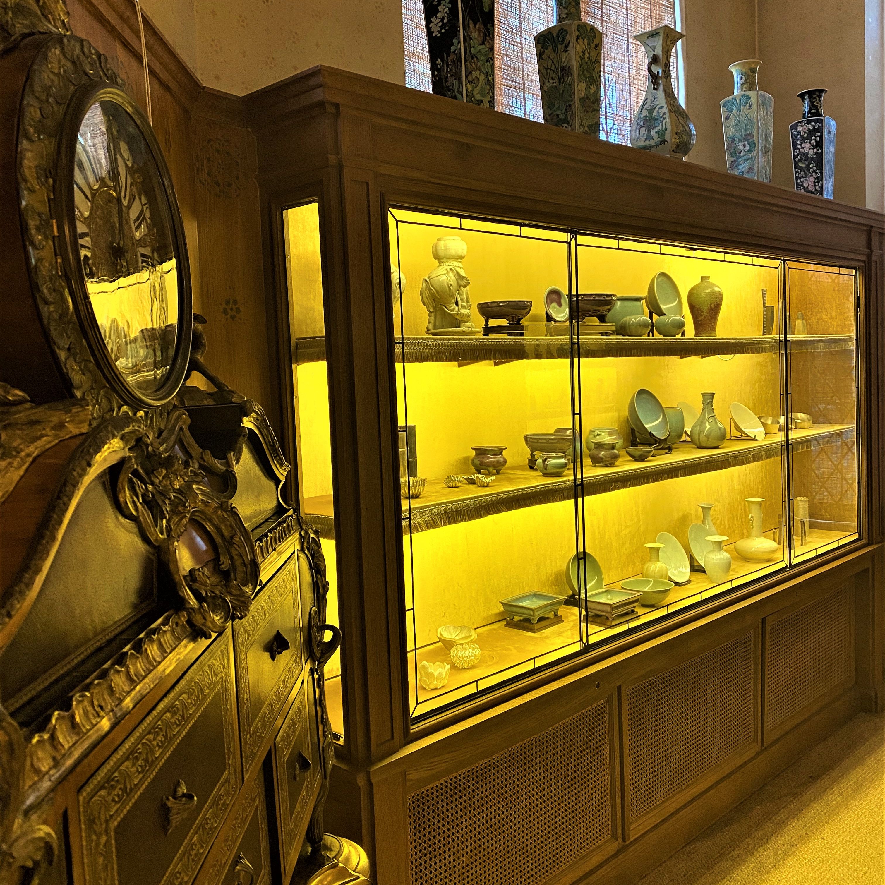 Display cabinet with various ceramic vases and artifacts in a museum or antique setting.
