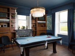 Elegant billiards room with blue pool table, chandelier, and large windows