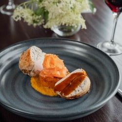 Gourmet chicken breast dish with sauce and garnish on a dark plate.