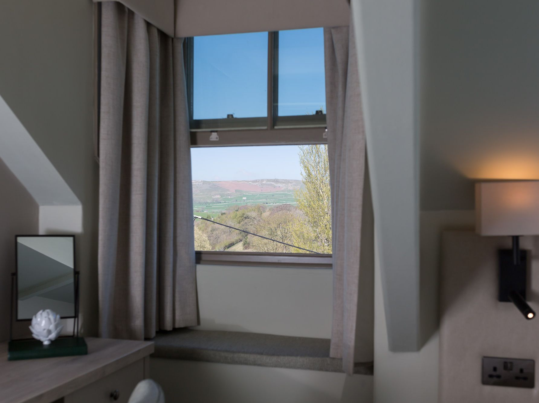 Room with a window view of the countryside and hills in the distance
