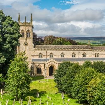 St. Andrews Church in Aysgarth surrounded by trees and gravestones