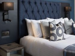 Modern bedroom with blue upholstered headboard and decorative pillows