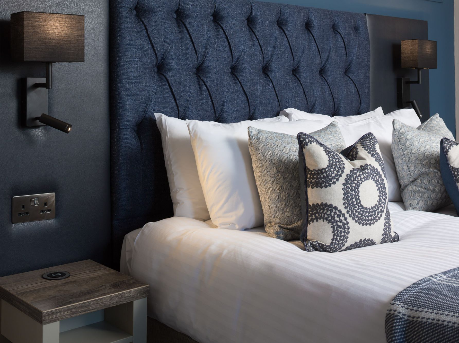 Modern bedroom with blue upholstered headboard and decorative pillows