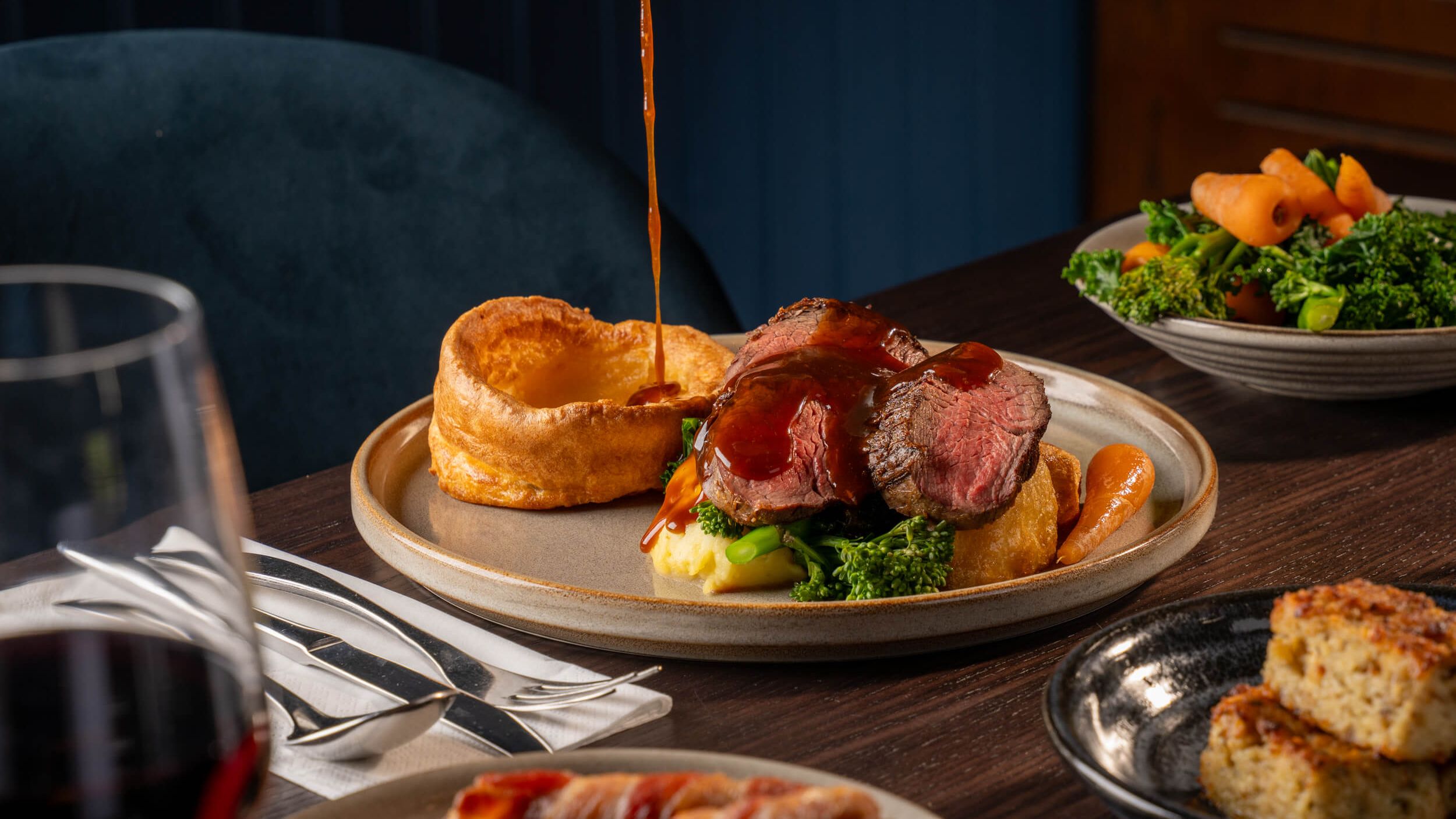 Roast beef dinner with Yorkshire pudding, vegetables and gravy being poured over the meat