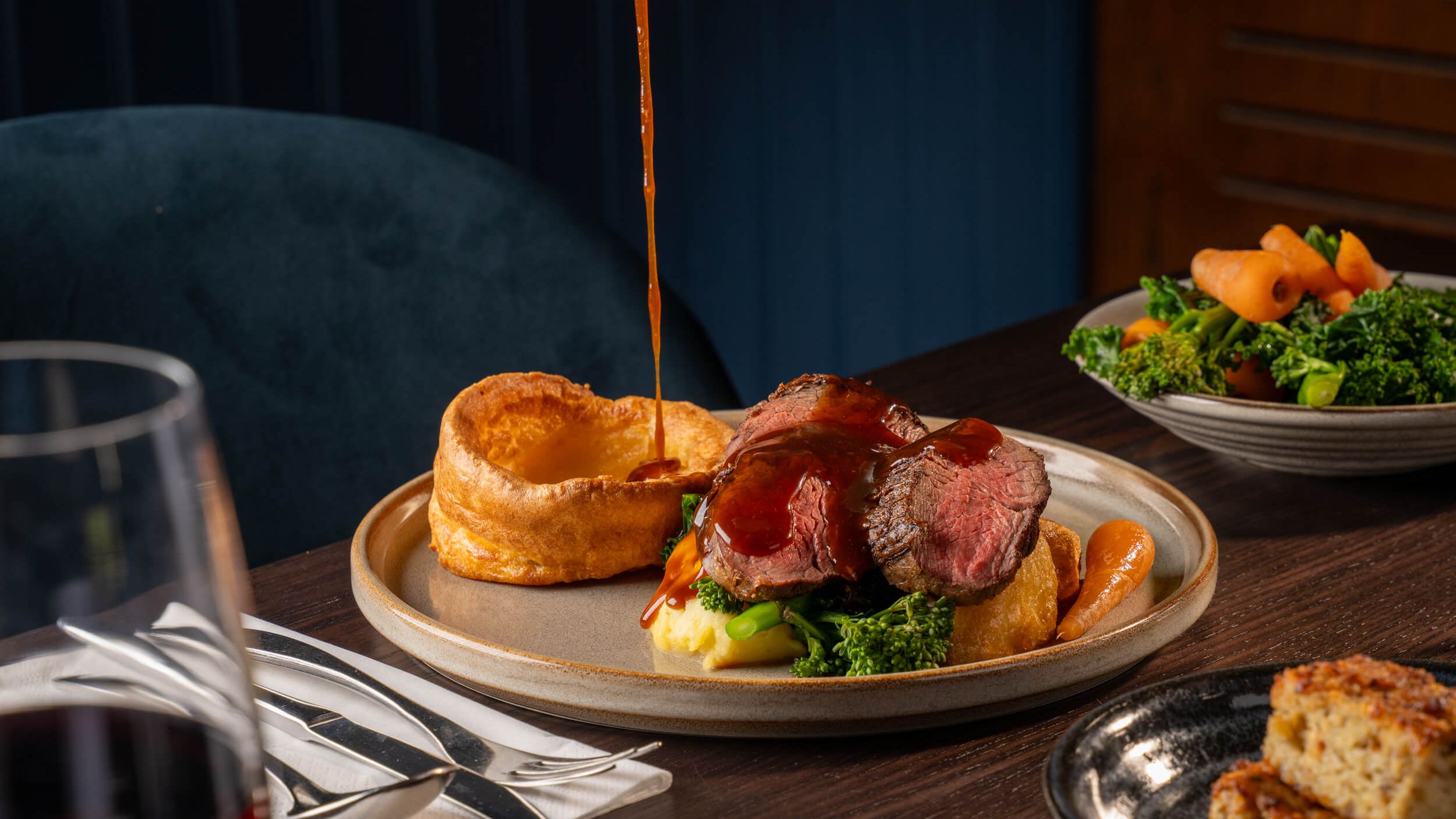 Roast beef dinner with Yorkshire pudding, vegetables and gravy being poured over the meat