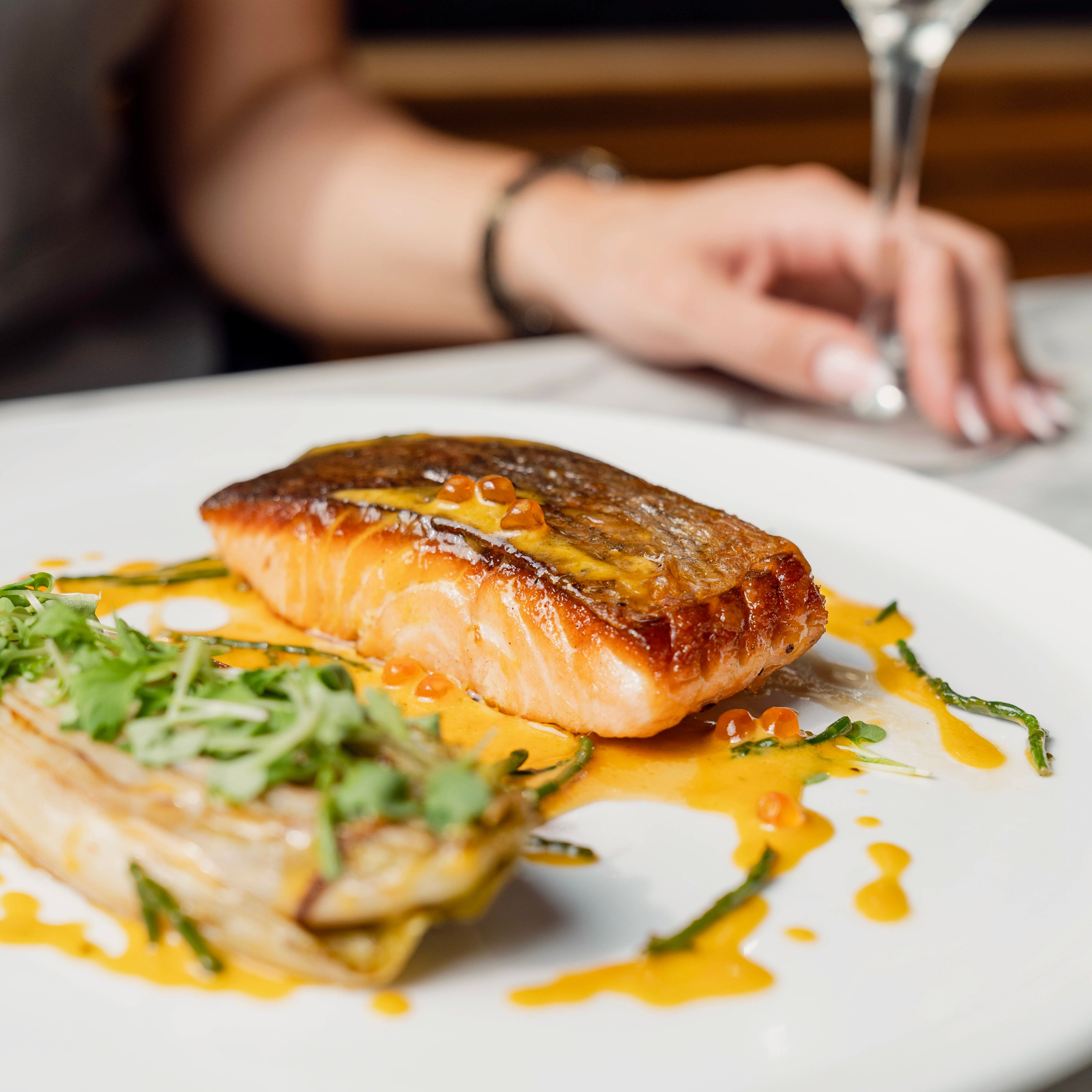 Grilled salmon fillet plated with garnish and sauce