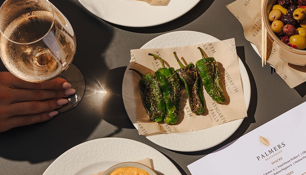A selection of tapas-style dishes and a glass of wine on an outdoor table at Aysgarth Falls Hotel.
