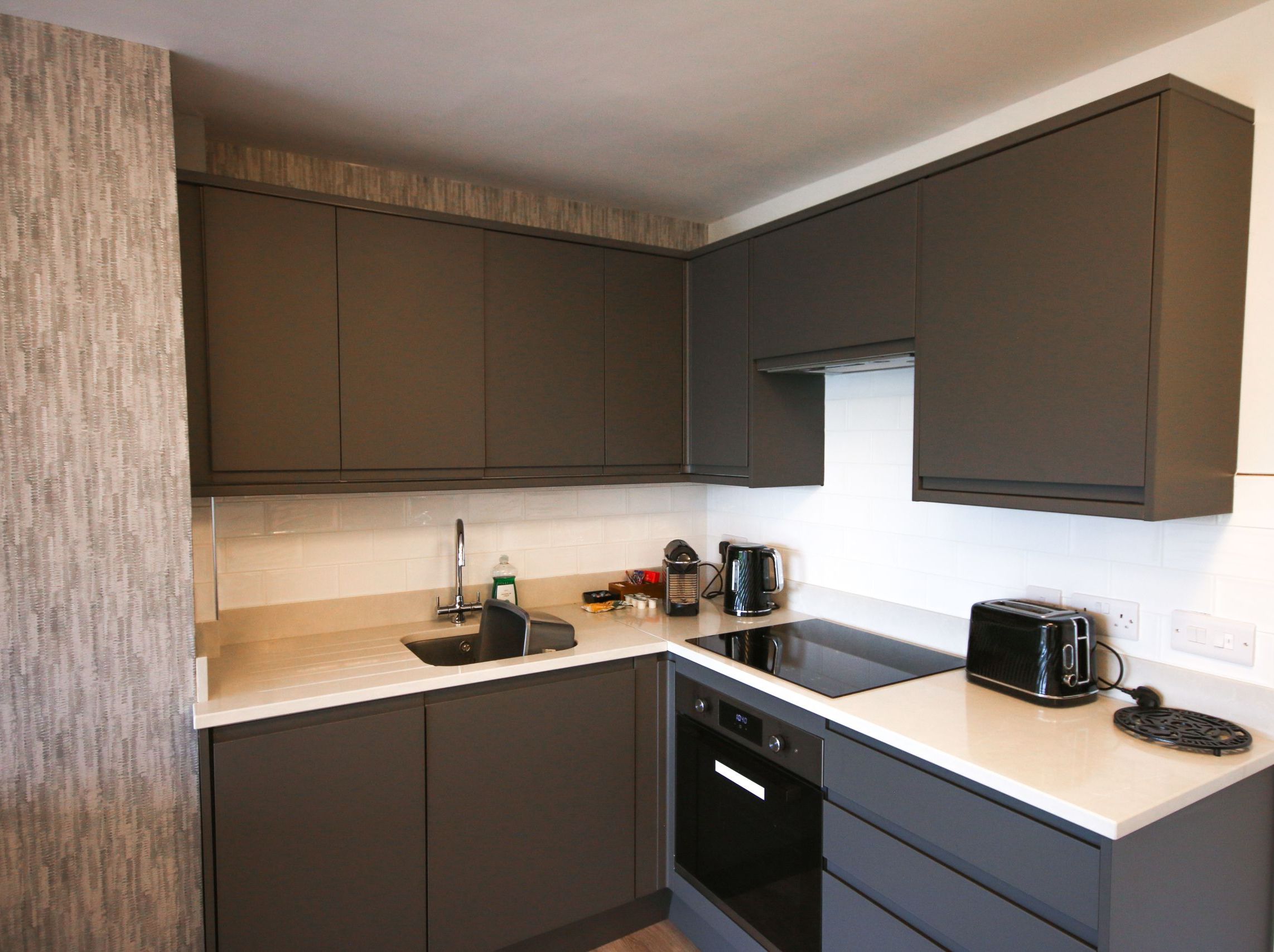 Modern kitchen with dark grey cabinets, white countertop, and appliances