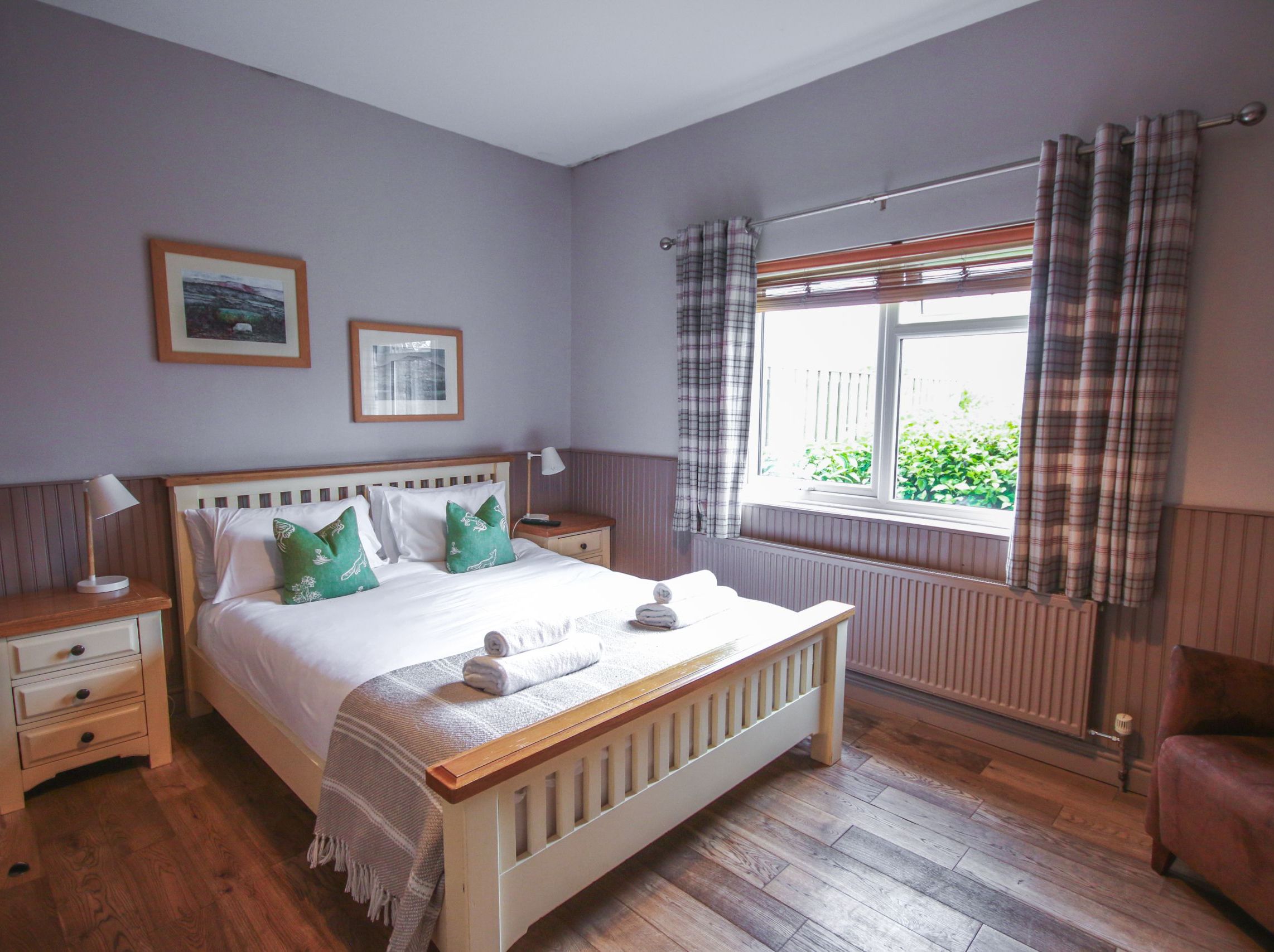 Cozy bedroom with a double bed, green pillows, and natural light from a window