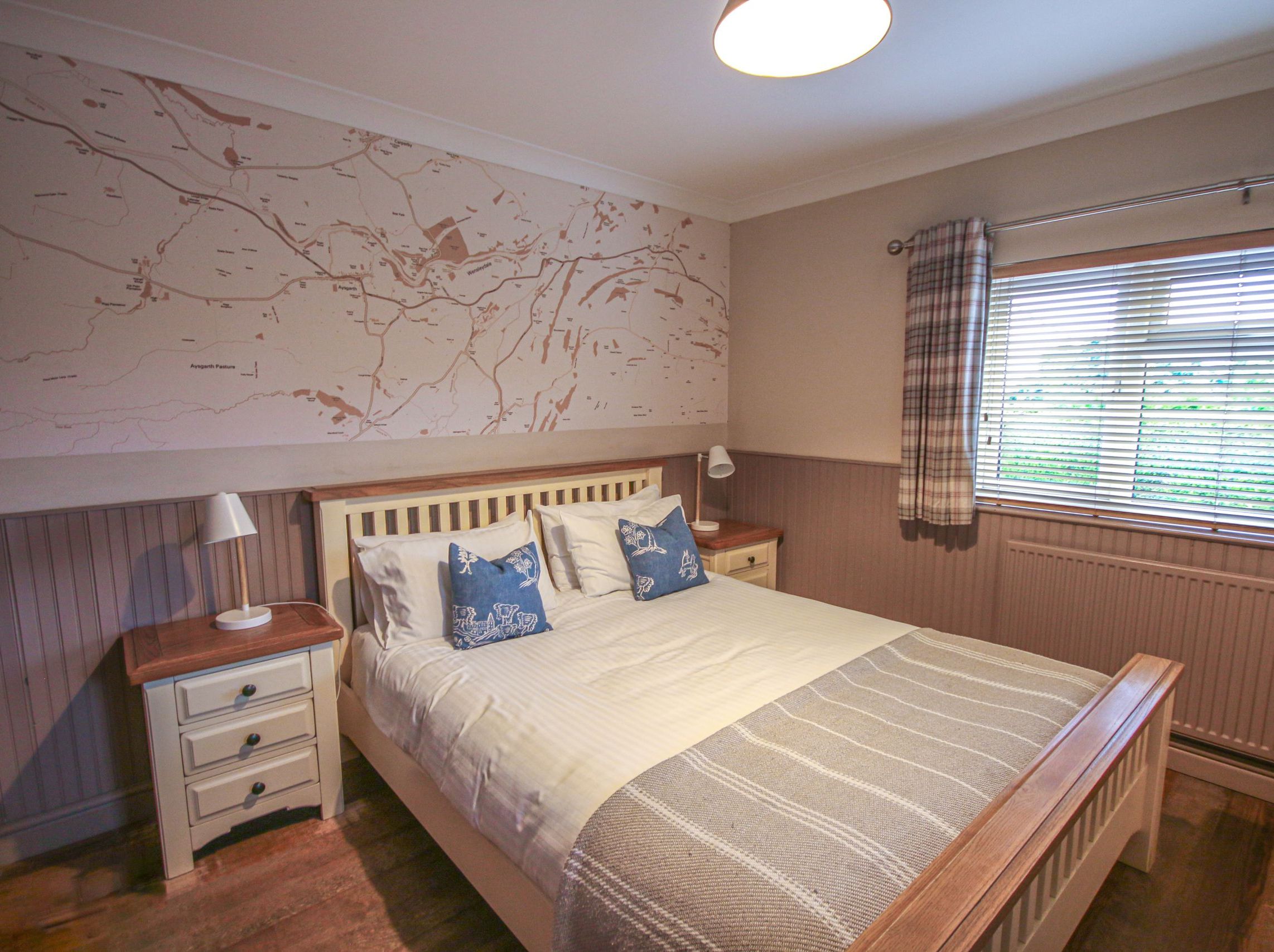 Cozy bedroom with a large bed and map-themed feature wall.