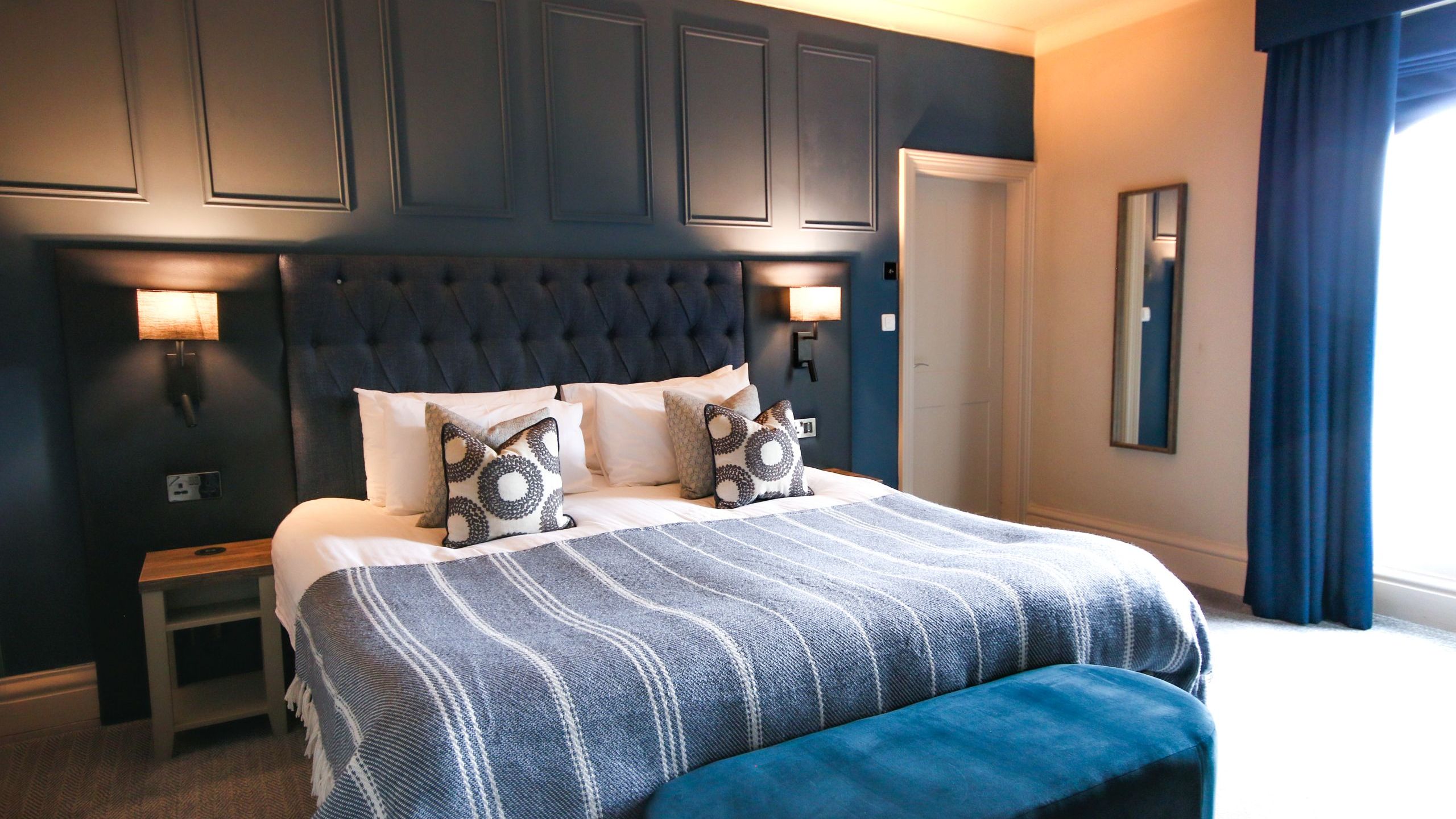 Modern bedroom with dark blue accents, a large bed, and stylish decor.