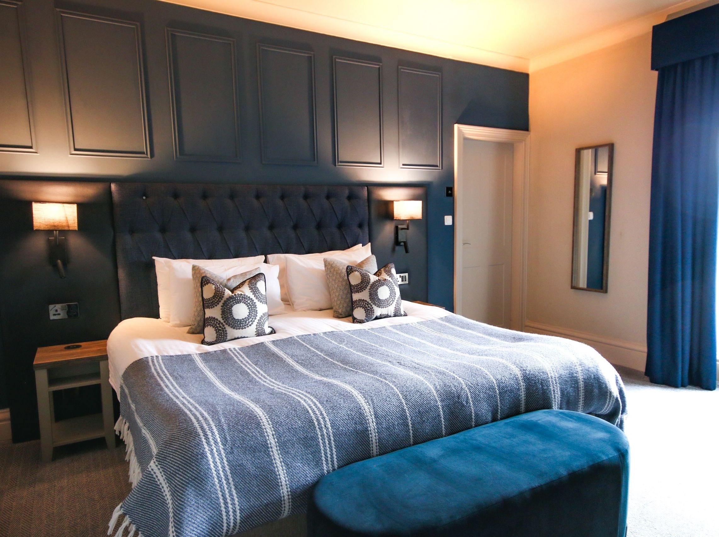 Modern bedroom with dark blue accents, a large bed, and stylish decor.