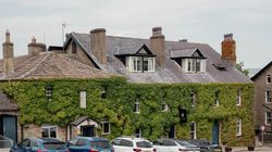 Stone building covered in green ivy with several parked cars in front