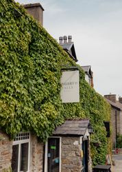 Stone building covered in thick green ivy with a sign reading 'Aysgarth Falls Hotel.'
