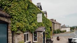 Stone building covered in green ivy on a quiet village street with a sign reading 'Aysgarth Falls Hotel'.
