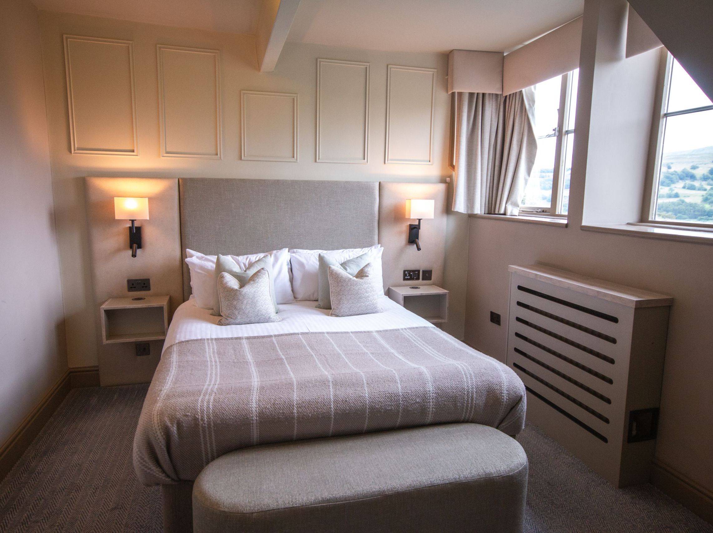 Cozy modern hotel bedroom with double bed and large windows