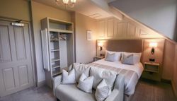 Cozy hotel room with a double bed, sofa, and open wardrobe under slanted ceiling