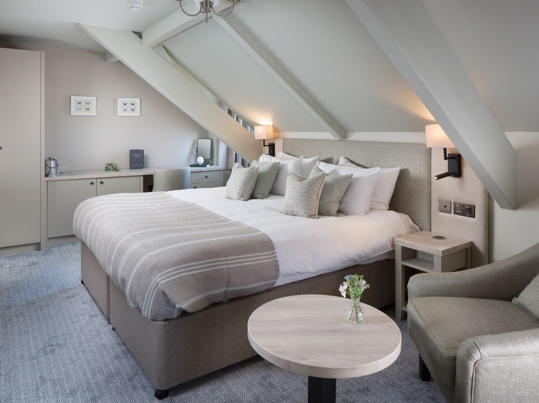 Modern hotel room with king-sized bed, armchair, and sloped ceiling