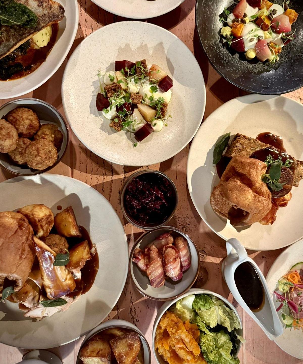 A festive party menu featuring a variety of beautifully plated dishes, including roasted meats, vegetables, Yorkshire puddings, and other side dishes.