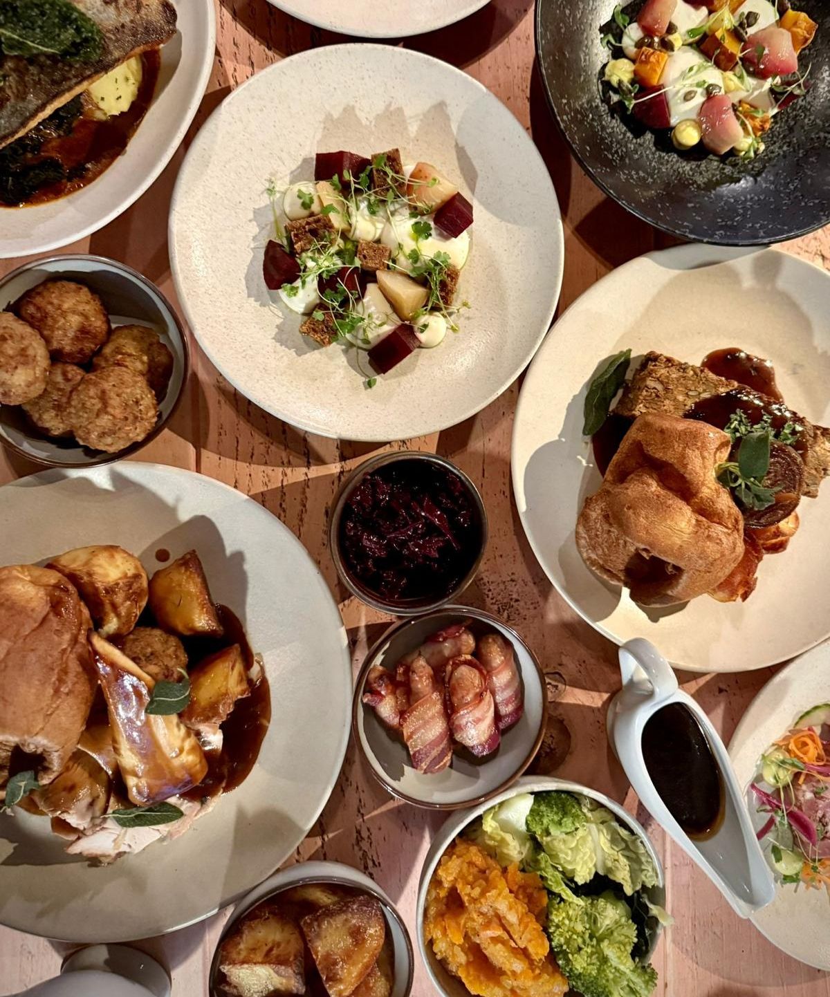 A festive party menu featuring a variety of beautifully plated dishes, including roasted meats, vegetables, Yorkshire puddings, and other side dishes.