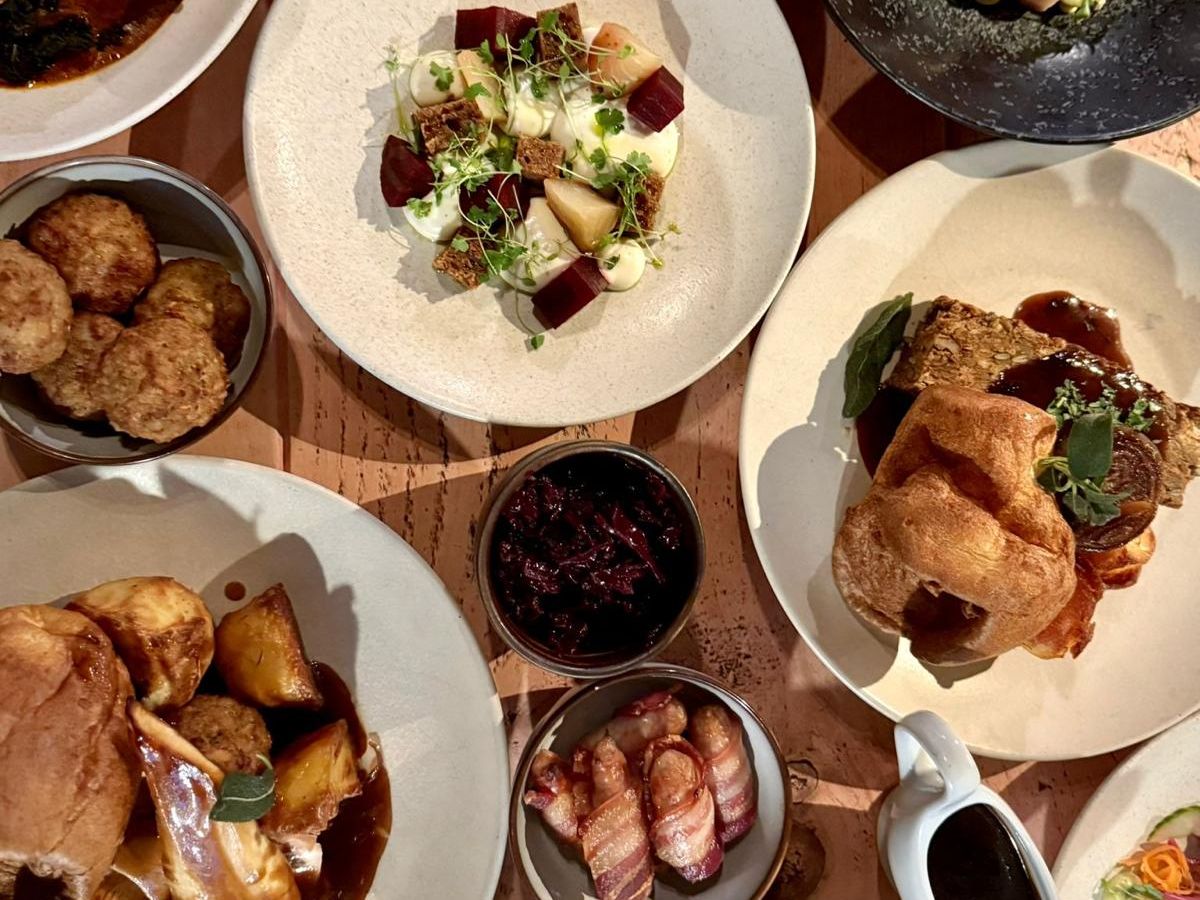 A festive party menu featuring a variety of beautifully plated dishes, including roasted meats, vegetables, Yorkshire puddings, and other side dishes.