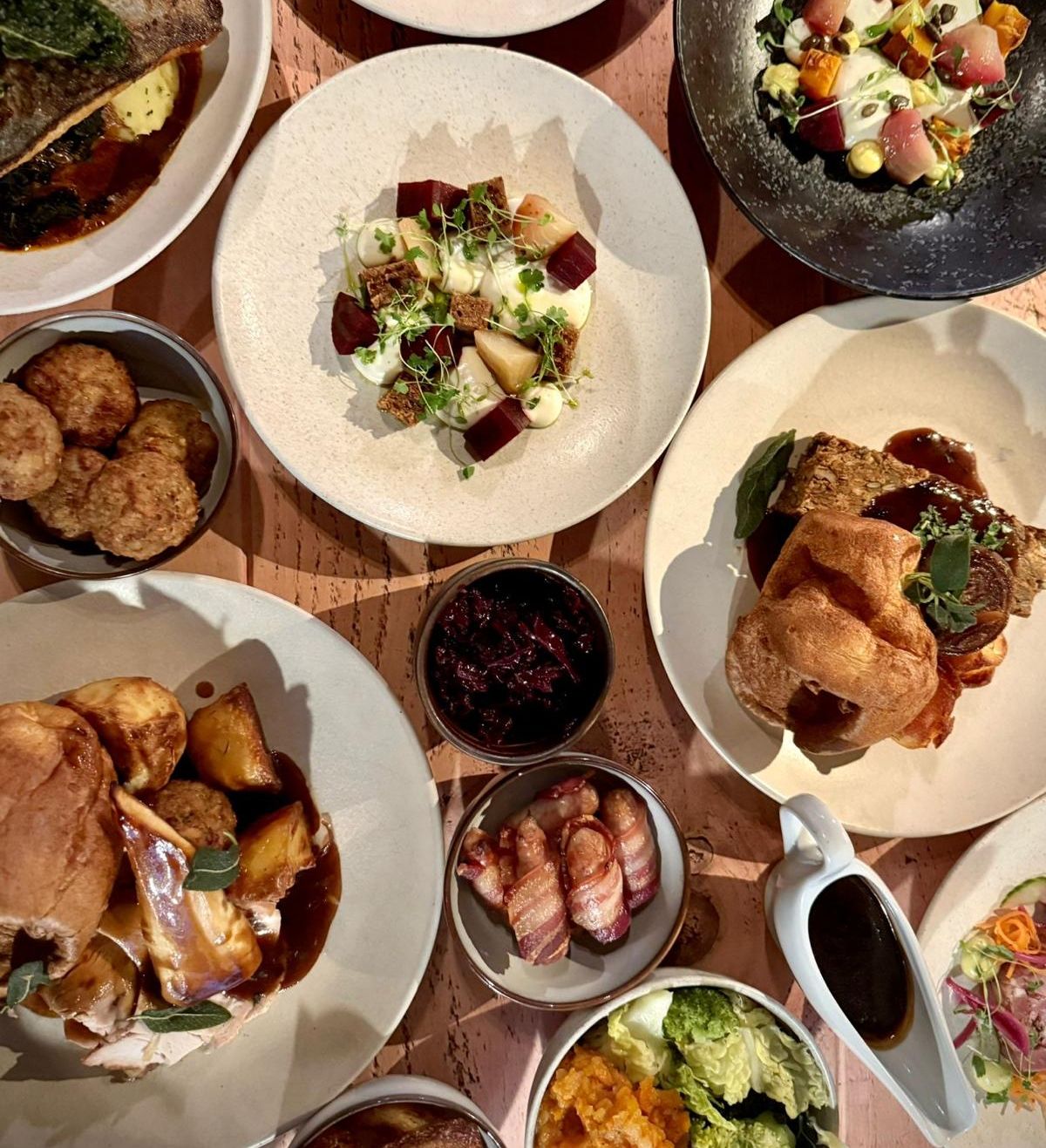 A festive party menu featuring a variety of beautifully plated dishes, including roasted meats, vegetables, Yorkshire puddings, and other side dishes.