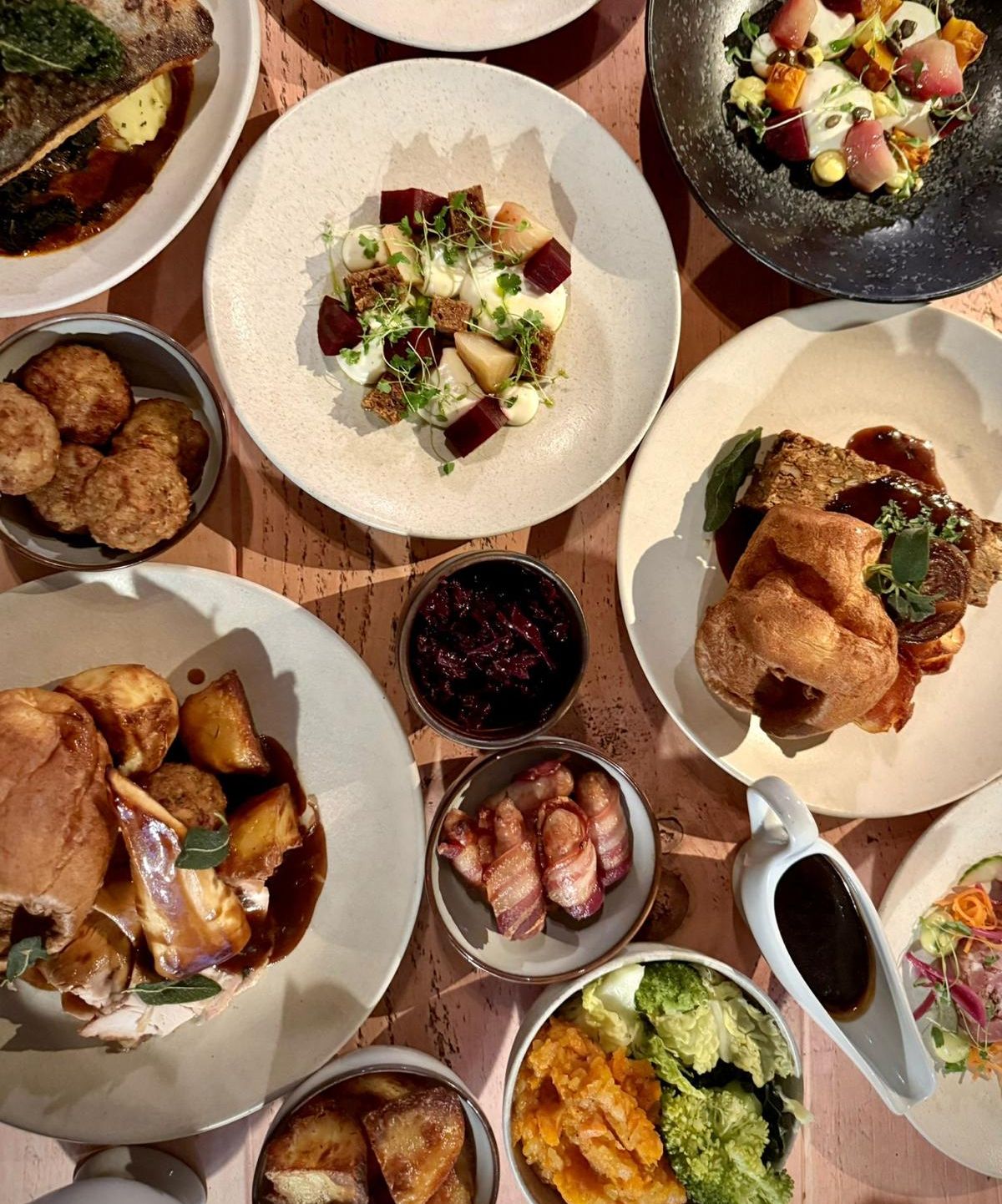 A festive party menu featuring a variety of beautifully plated dishes, including roasted meats, vegetables, Yorkshire puddings, and other side dishes.