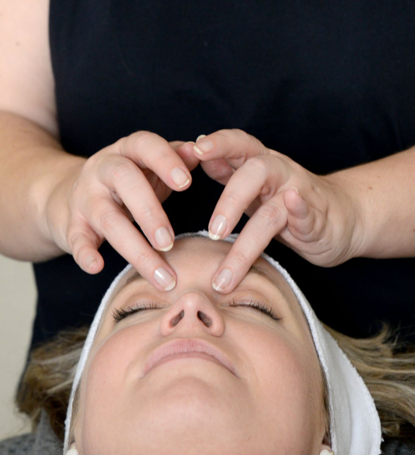 Person receiving a facial massage, with hands gently pressing on their forehead
