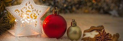 Christmas decorations including ornaments, a star-shaped lantern, cookies, cinnamon sticks, and star anise on a snowy surface