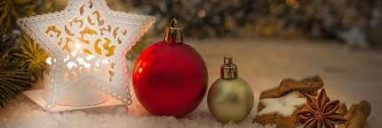 Christmas decorations including ornaments, a star-shaped lantern, cookies, cinnamon sticks, and star anise on a snowy surface