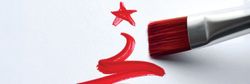 Red paintbrush painting a Christmas tree shape and star on white paper
