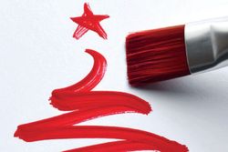 Red paintbrush painting a Christmas tree shape and star on white paper