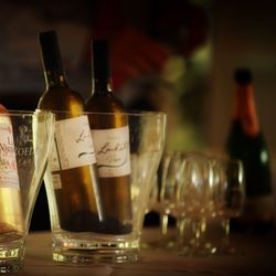 Bottles of wine in ice buckets with wine glasses and champagne in the background
