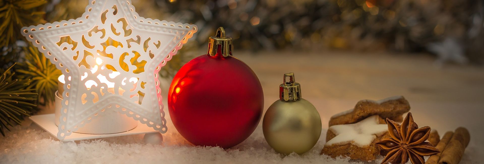 Christmas decorations with a glowing star lantern, red and gold ornaments, cinnamon sticks, star anise, and cookies on snow