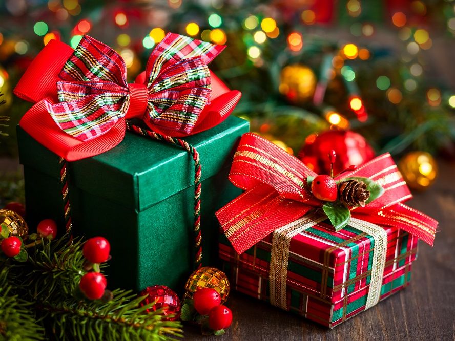 Two Christmas gift boxes with festive bows surrounded by holiday decorations and lights
