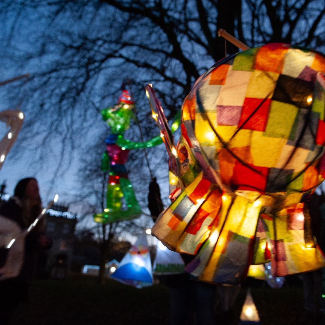 Colorful lanterns shaped like animals and fantasy figures being carried during an outdoor evening event