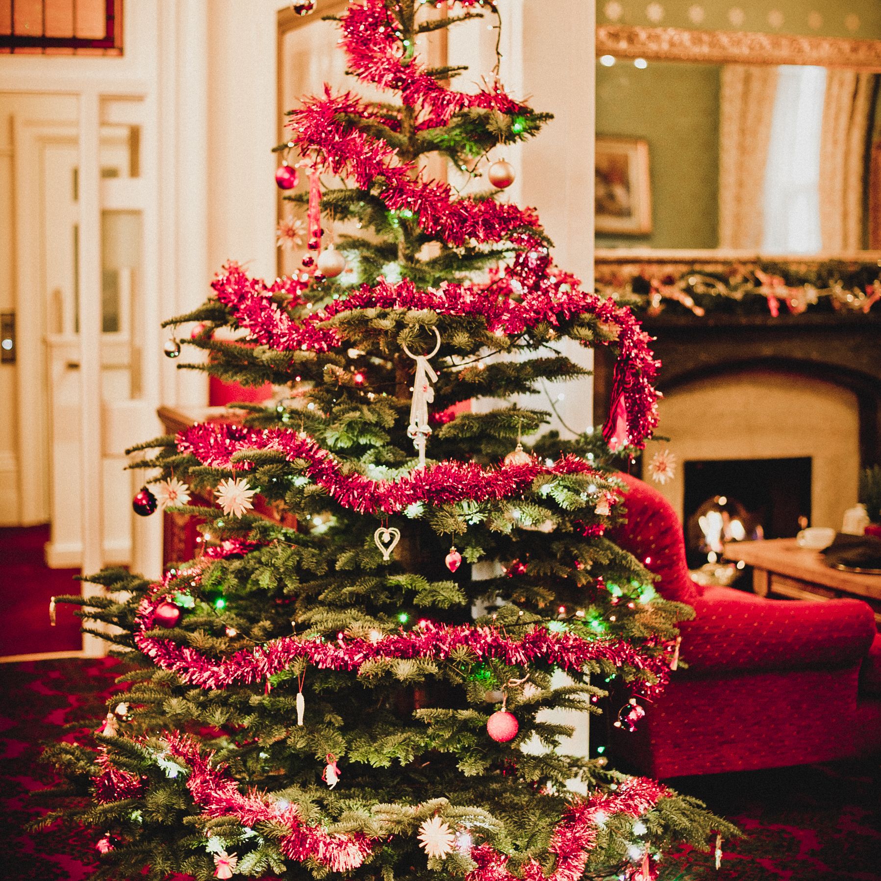 Decorated Christmas tree with red tinsel and ornaments in a cozy living room