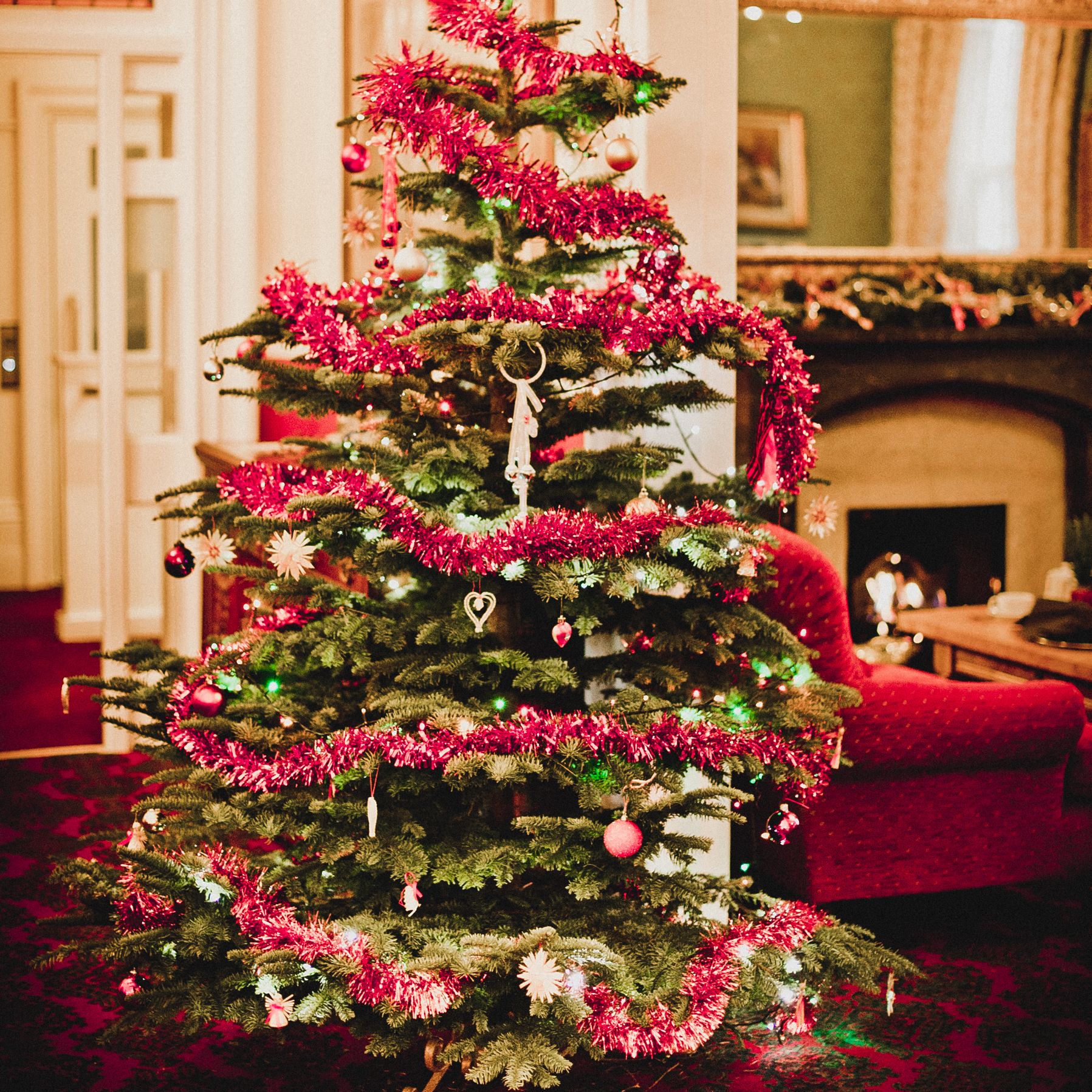 Decorated Christmas tree with red tinsel and ornaments in a cozy living room