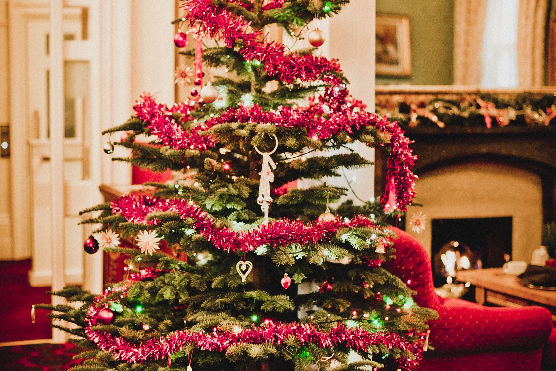 Decorated Christmas tree with red tinsel and ornaments in a cozy living room