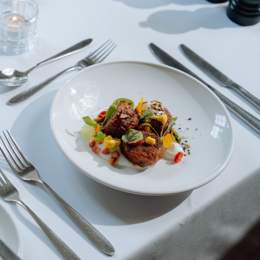 Elegant table setting with a gourmet dish and bread rolls