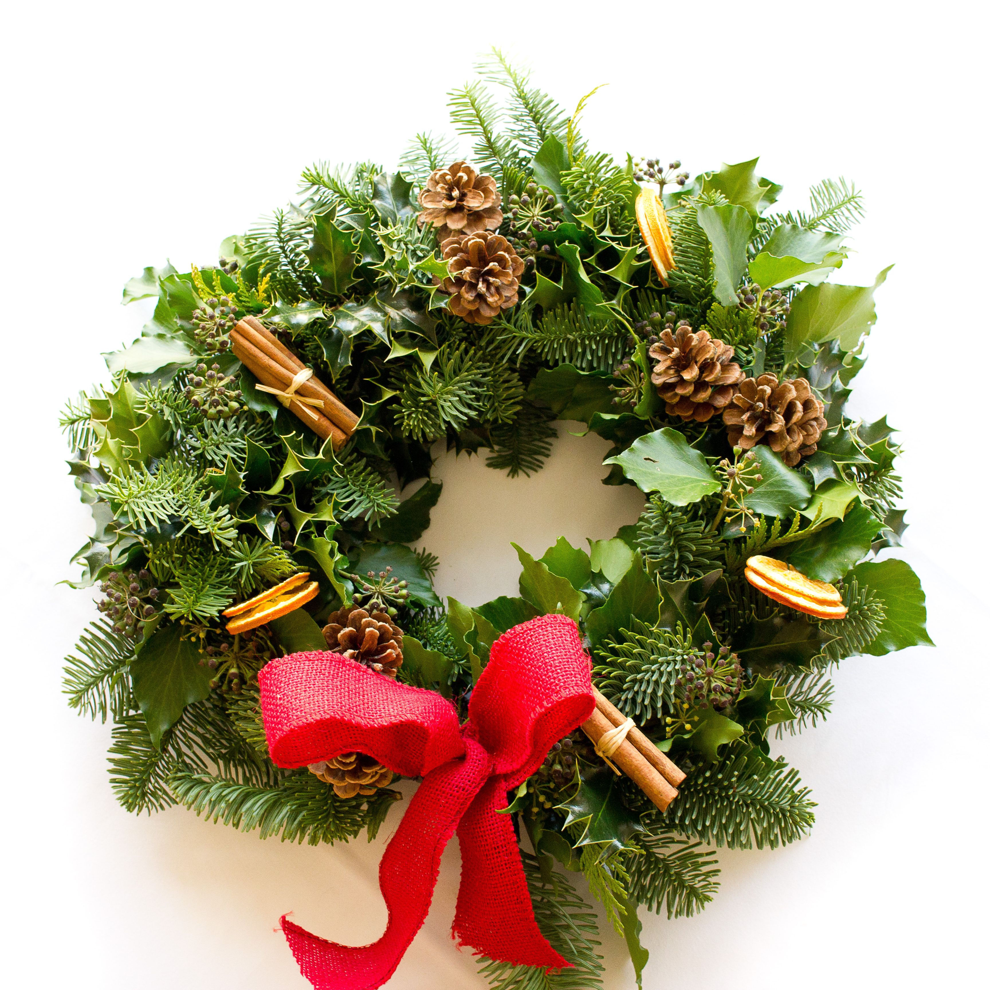 Festive holiday wreath decorated with pinecones, cinnamon sticks, dried orange slices, and a red bow