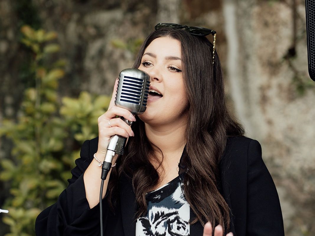 Woman singing into a retro microphone outdoors