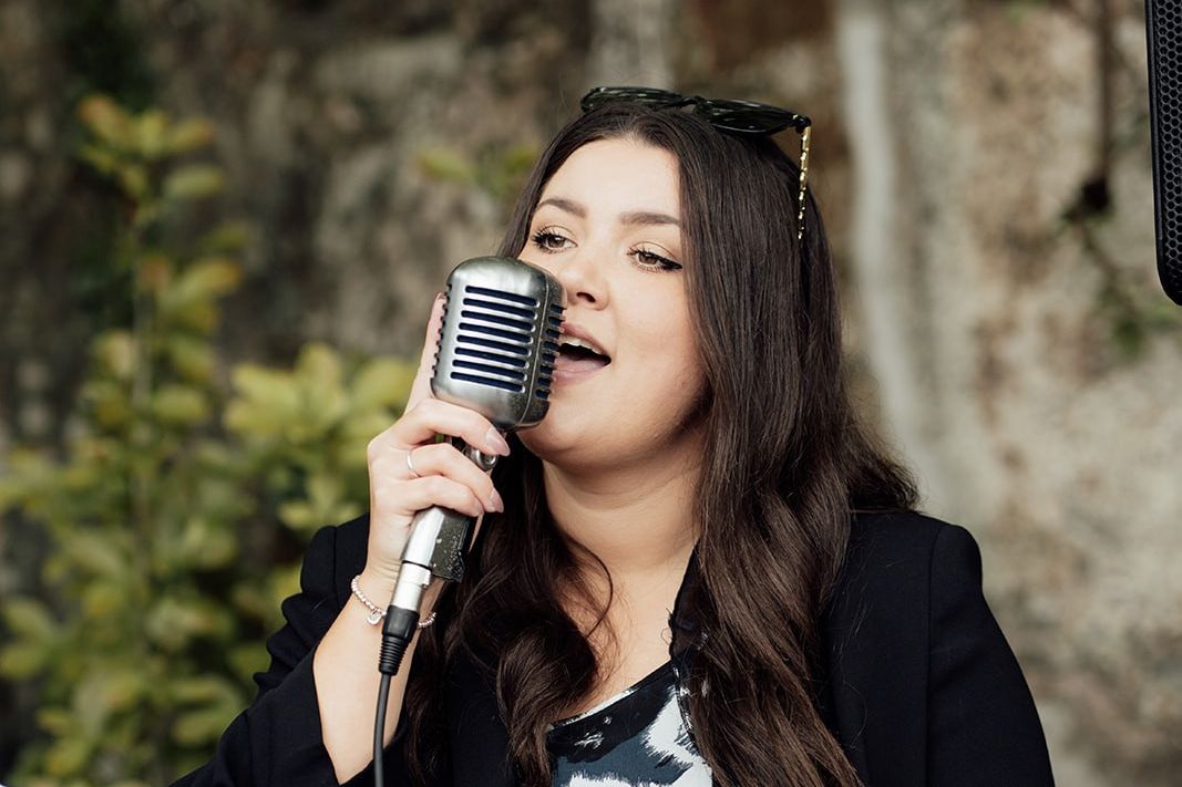 Woman singing into a retro microphone outdoors