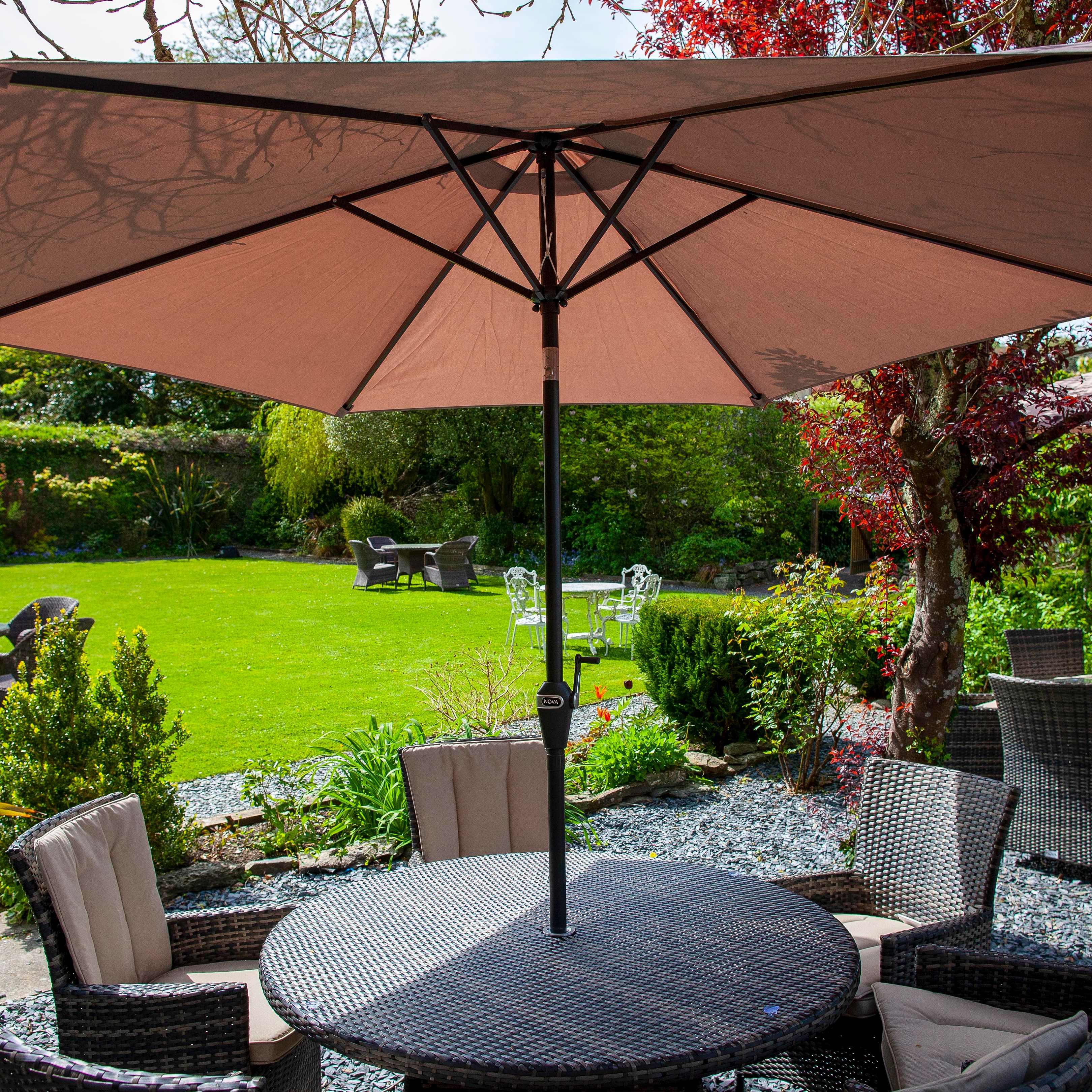 Outdoor patio area with wicker furniture and a large umbrella shade in a garden setting